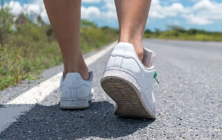 close up of a person wearing sneakers walking on a paved surface